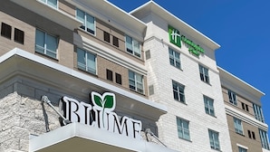 Un edificio de hotel de varios pisos con un llamativo letrero 'URBANE' y un logotipo verde encima.