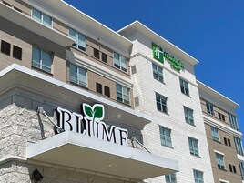 Un edificio de hotel de varios pisos con un llamativo letrero 'URBANE' y un logotipo verde encima.