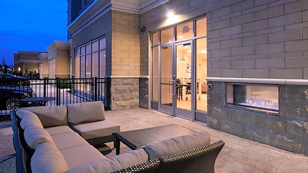 An outdoor patio with a stone wall, a glass door entrance, and a built-in fireplace.