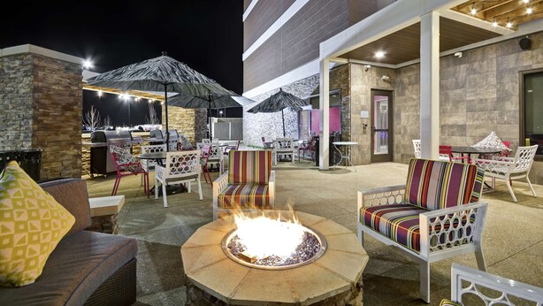 An outdoor patio area with seating, a fire pit, and a grill. - Home2 Suites by Hilton KCI Airport (Kansas City)