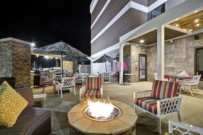 Ein Patio im Freien mit Sitzgelegenheiten, einem Feuerkorb und einem Grill.