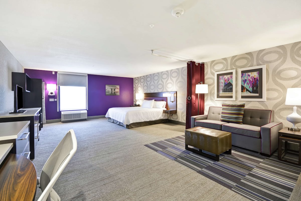 Une chambre d’hôtel avec un lit, un canapé, un bureau et une chaise.
