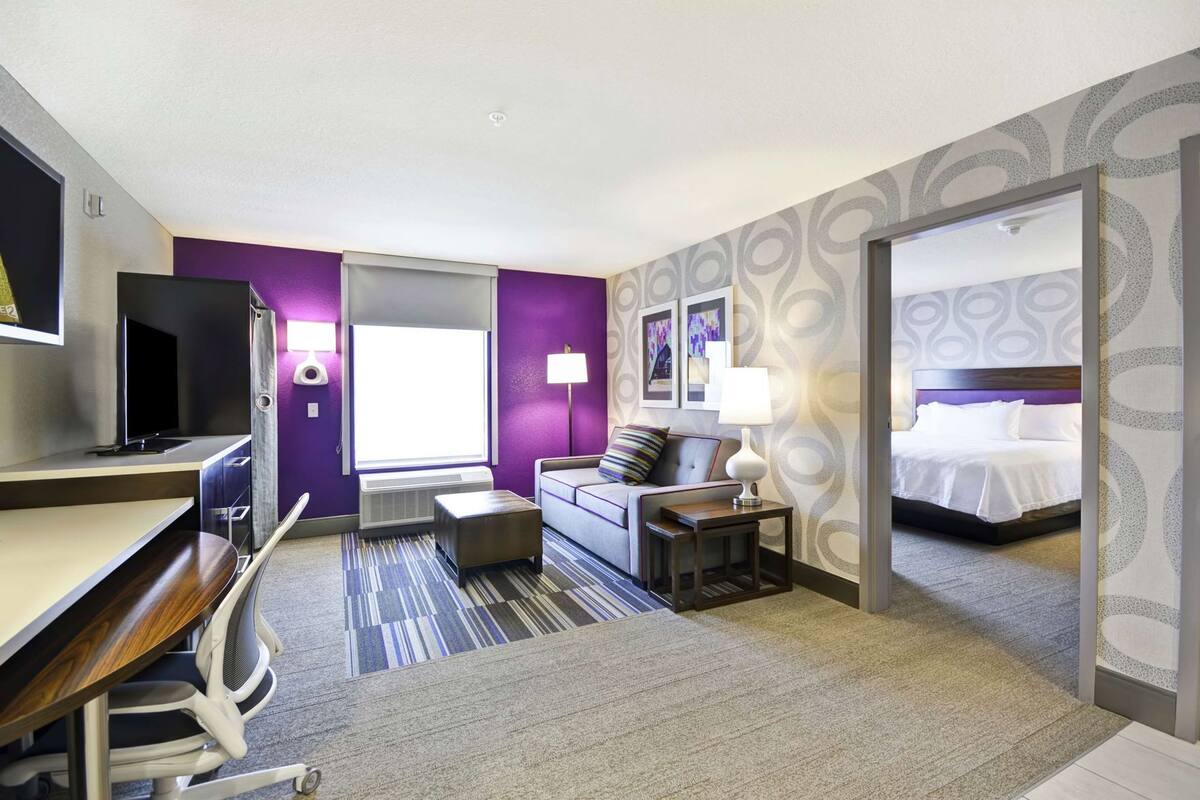 Une chambre d’hôtel comprenant un lit, un canapé, un bureau avec une chaise, une télévision et une salle de bain.