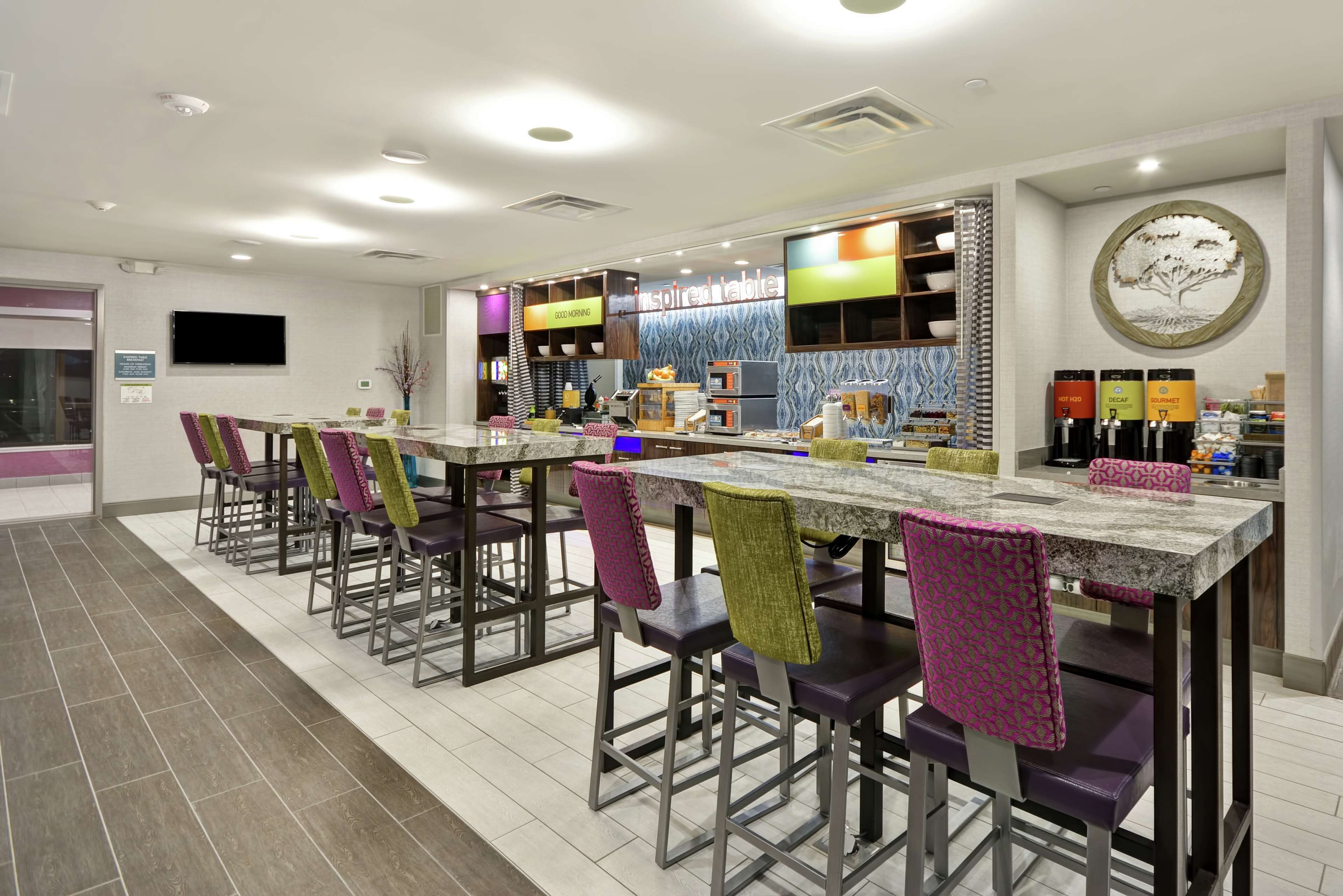 Un restaurante moderno con una barra larga, taburetes y diversas opciones de asientos.