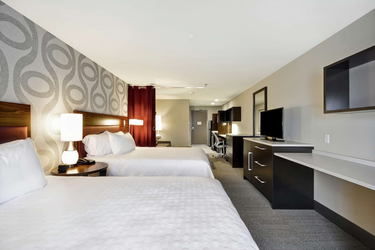 Une chambre d’hôtel avec deux lits, un bureau, une télévision et un miroir.