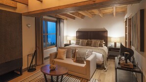 A hotel room with a bed, a sofa, a small table, a lamp, and a window with curtains. - La Casa Rodavento - Adults Only (Valle de Bravo)