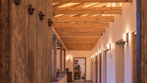 A corridor with wooden beams and tiled flooring, leading to a room with a fireplace and a framed picture on the wall. - La Casa Rodavento - Adults Only (Valle de Bravo)
