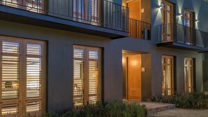 A modern multi-story building with large windows and balconies, featuring a well-lit entrance and a gravel driveway. - La Casa Rodavento - Adults Only (Valle de Bravo)
