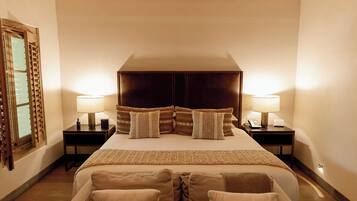 Un dormitorio con una cama grande, vigas de madera, dos mesitas de noche con lámparas y un sofá.