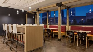 Un restaurante moderno con vigas de madera, taburetes de bar y cabinas.