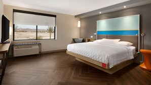 Un dormitorio moderno con cama, televisión, calefacción y vistas al desierto.