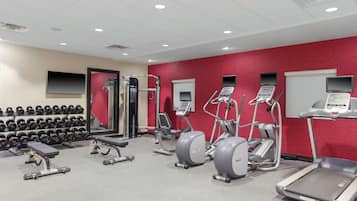 A gym with treadmills, elliptical machines, and dumbbells.