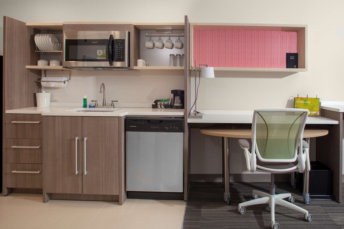 A compact kitchenette with a microwave, coffee maker, and dishwasher.
