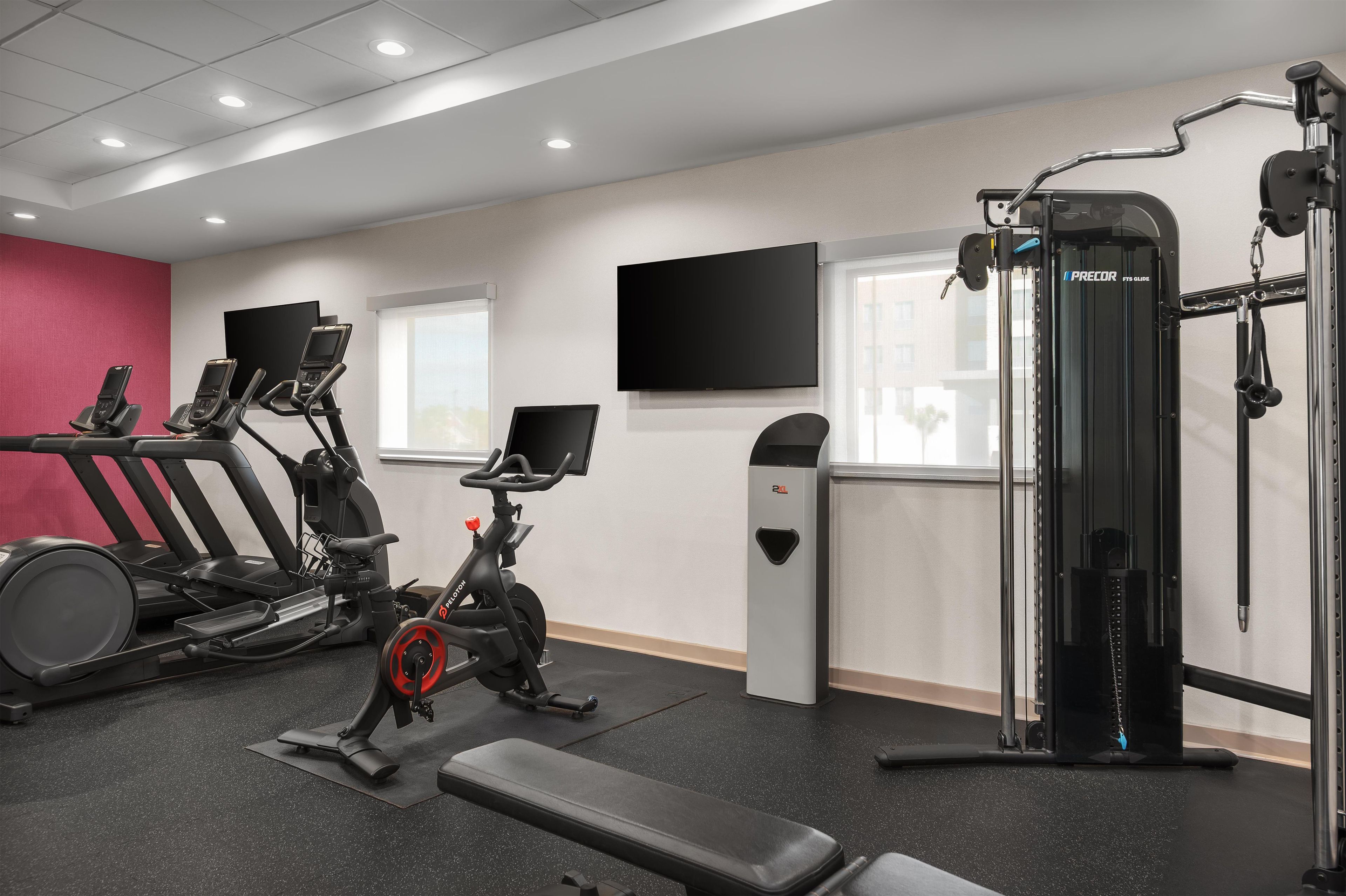 A gym with treadmills, an elliptical, a weight machine, and a TV on the wall.