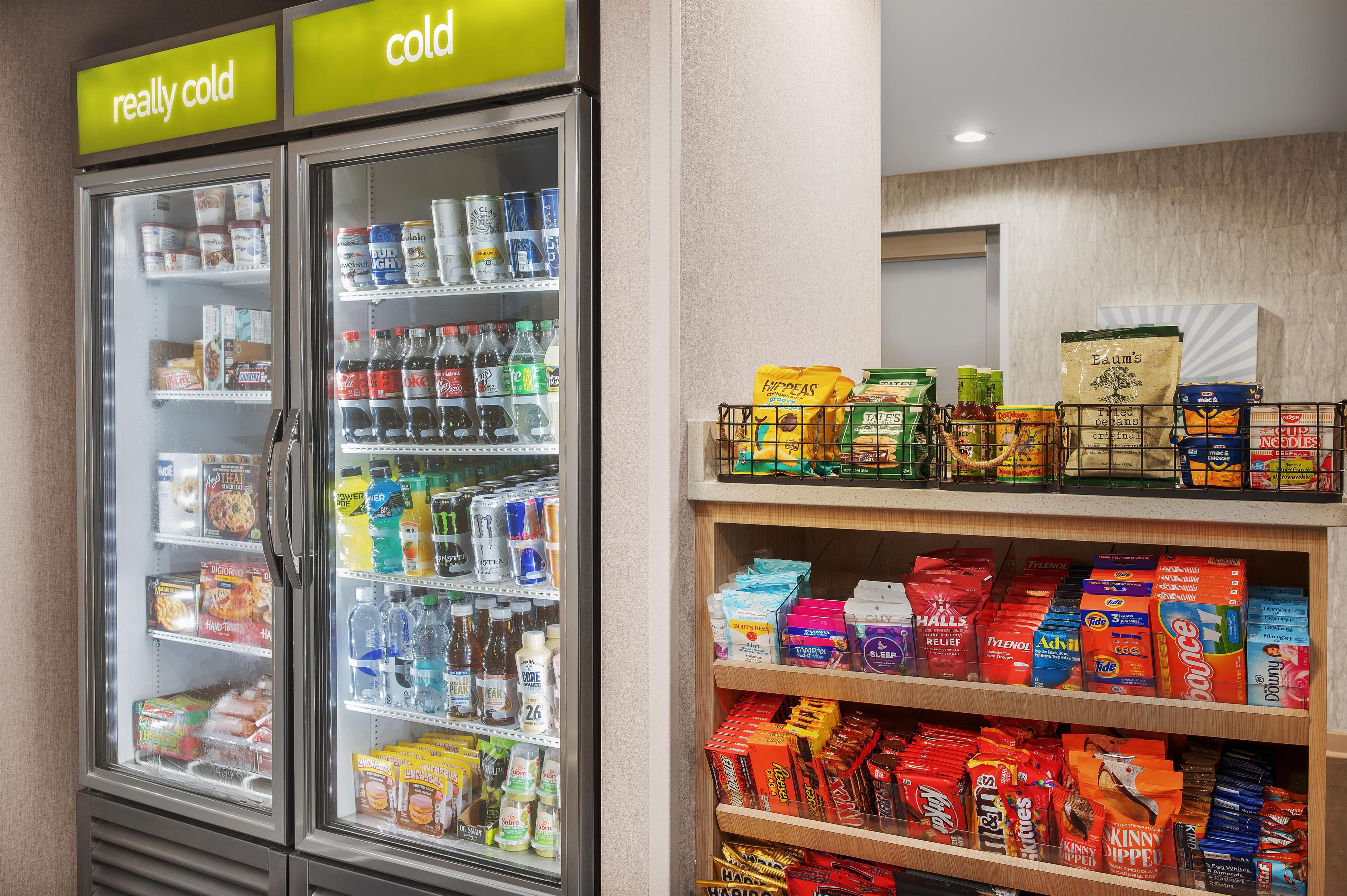 A refrigerated display case with beverages and snacks, and a shelf with various packaged goods.