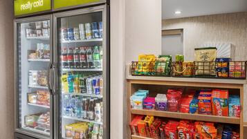 A refrigerated display case with beverages and snacks, and a shelf with various packaged goods.