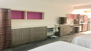 A hotel room with two beds, a desk with a chair, a television, and a microwave.