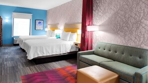 Une chambre d’hôtel avec deux lits, un canapé, un tapis coloré et un papier peint à motifs.