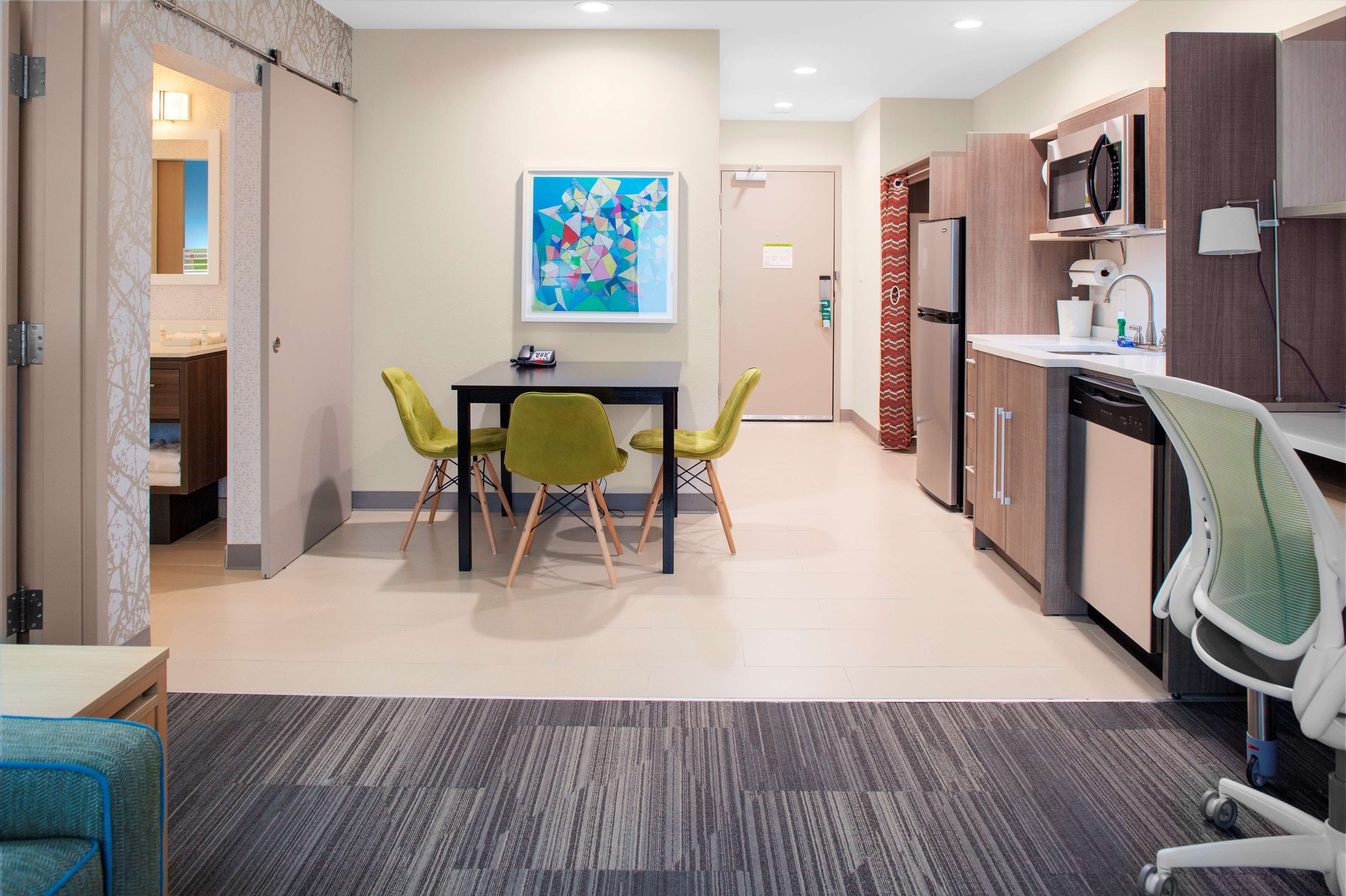A modern kitchen with a microwave, sink, and dishwasher. There is a dining area with a table and chairs.