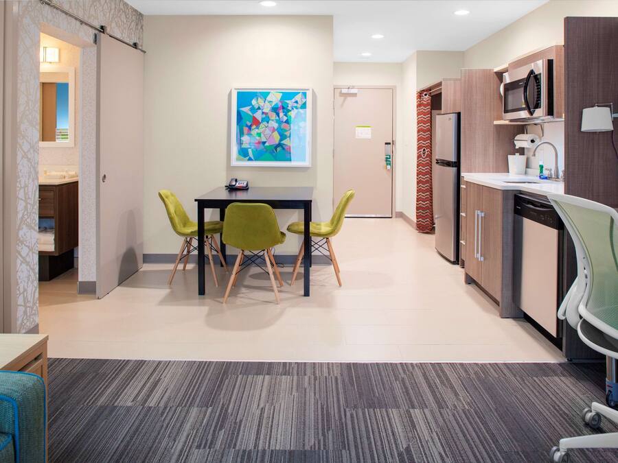 A modern kitchen with a microwave, sink, and dishwasher. There is a dining area with a table and chairs.