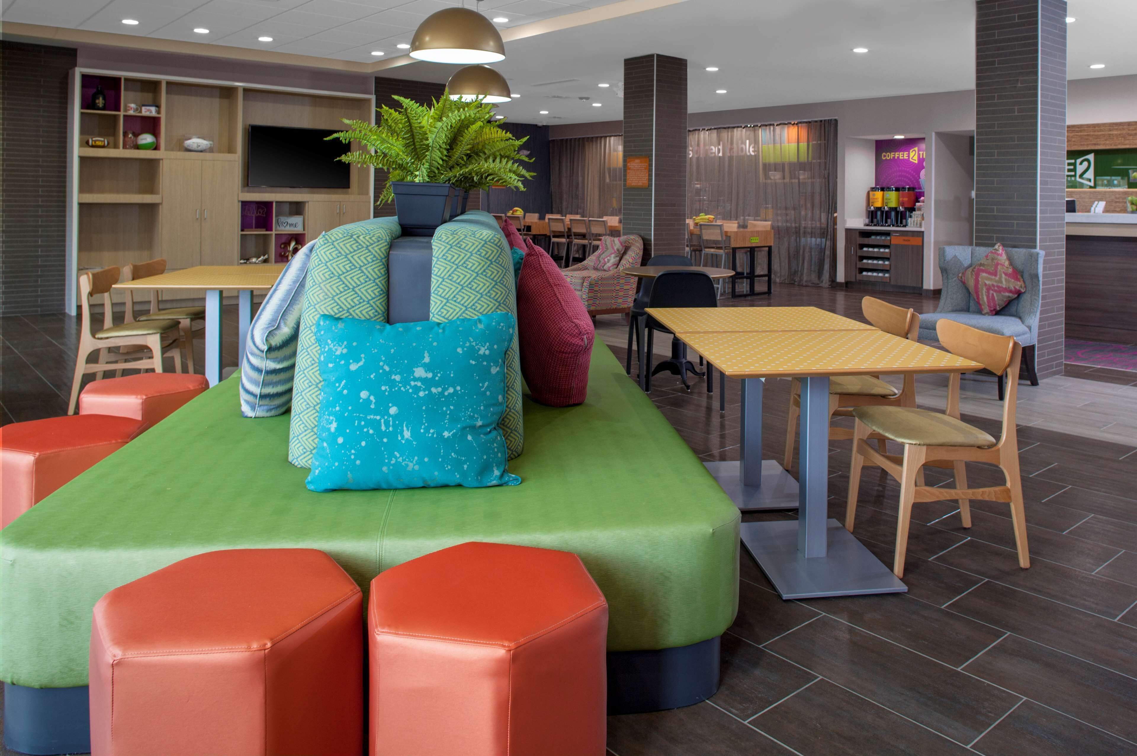 Un área de lounge moderna con disposiciones de asientos, una barra de café y una pantalla de televisión.