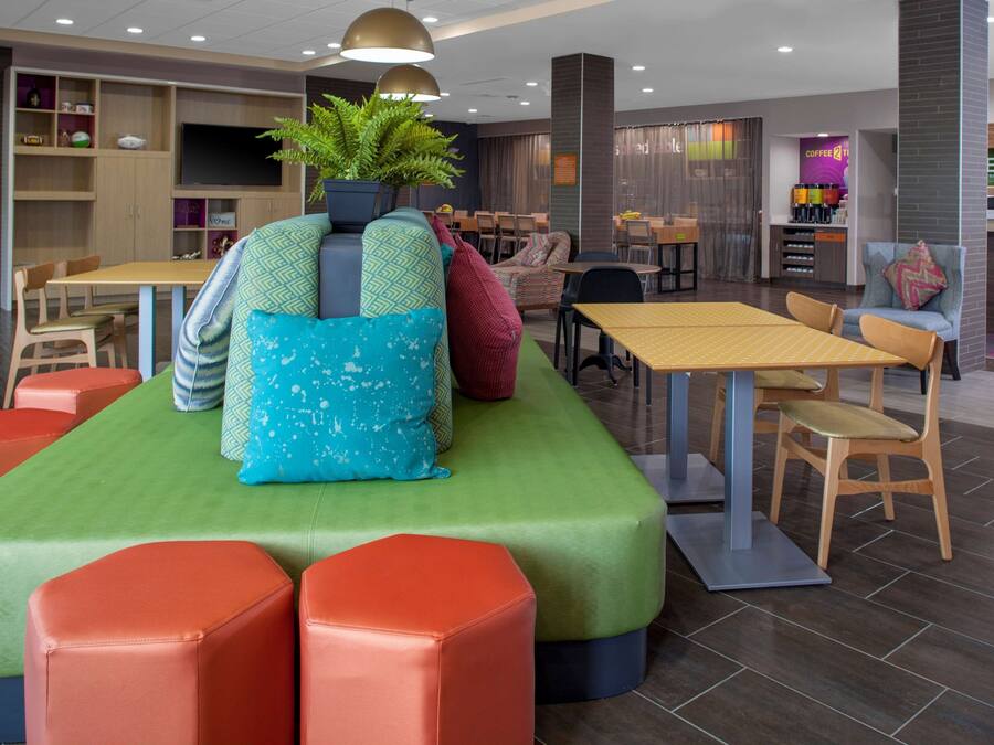 Un área de lounge moderna con disposiciones de asientos, una barra de café y una pantalla de televisión.