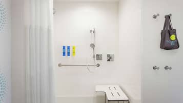 A modern bathroom with a shower, grab bars, and a towel rack.