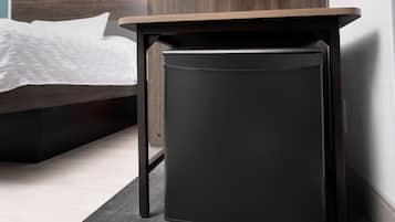 A compact black side table with a wooden top, positioned next to a bed with a white textured bedspread.