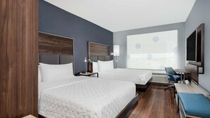 Une chambre d’hôtel avec deux lits, un bureau, une chaise, une télévision et une grande fenêtre donnant sur un beau paysage.
