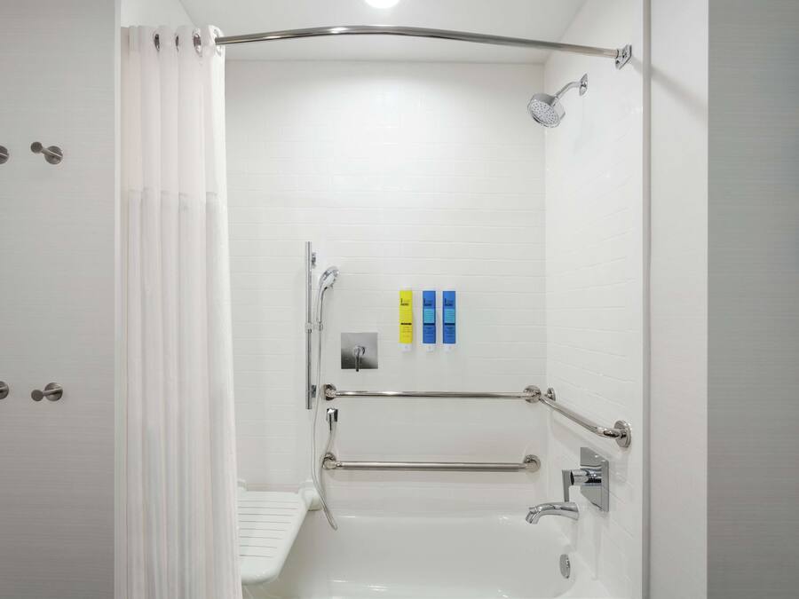 Uma casa de banho moderna com banheira, chuveiro e barras de apoio.