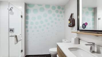 A modern bathroom with a glass shower enclosure, a toilet, and a sink with a wooden vanity.