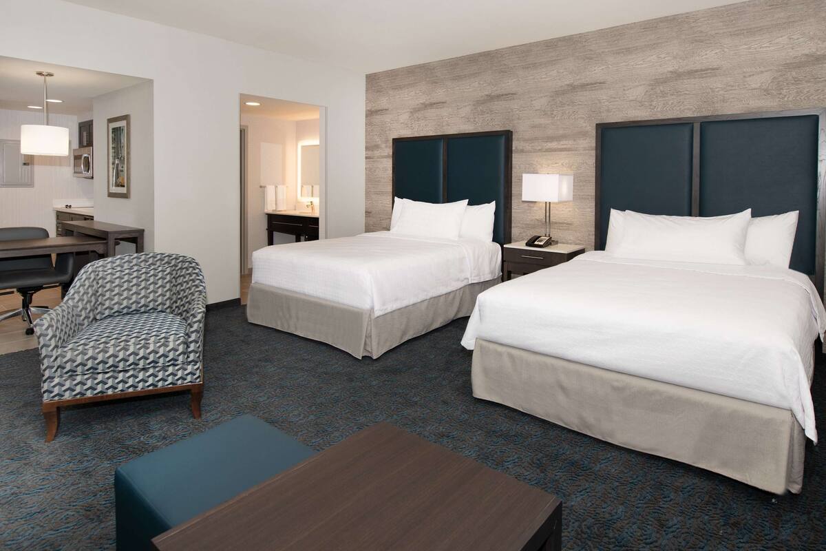 Een hotelkamer met twee bedden, een bureau, een stoel en een tafeltje.
