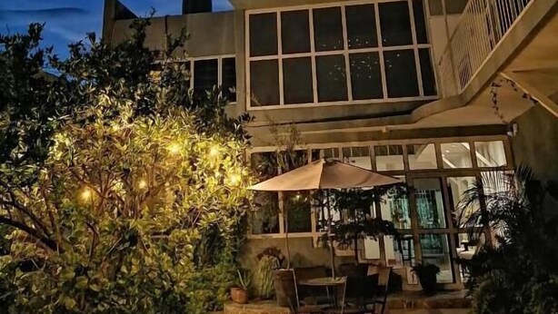 A building with a large glass facade and a patio area with outdoor furniture. - Casa Massima Hotel (León)