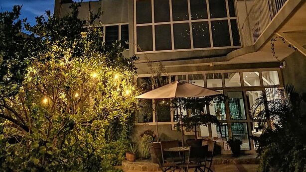 A building with large windows and a patio area with outdoor furniture and plants. - Casa Massima Hotel (León)