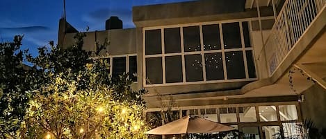 A building with large windows and a patio area with outdoor furniture and plants.