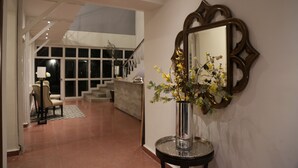 A hallway with a mirror, a vase with flowers, and a staircase in the background. - Casa Massima Hotel (León)