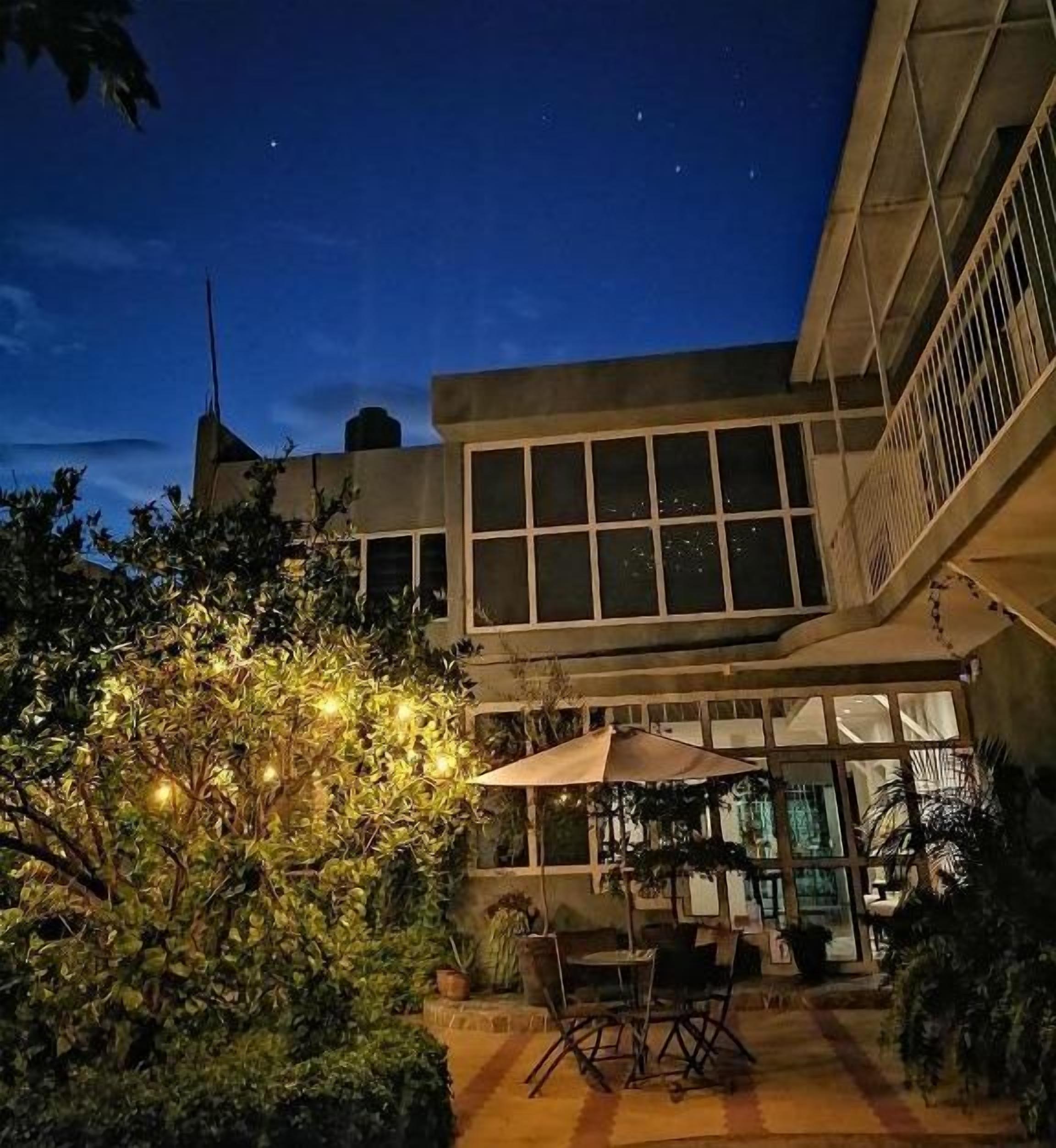Un edificio con un amplio ventanal y un patio con mobiliario exterior.