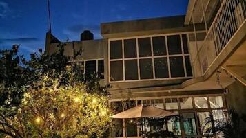 Un edificio con un amplio ventanal y un patio con mobiliario exterior.
