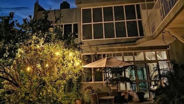 A building with a large glass facade and a patio area with outdoor furniture. - Casa Massima Hotel (León)