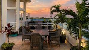A rooftop terrace with a table and chairs, potted plants, and a view of the cityscape at sunset. - PUNTA ESMERALDA Hotel Boutique (Playa del Carmen)