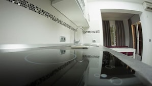 A modern kitchen with a black countertop, a built-in stove, and a small dining area with a table and chairs.