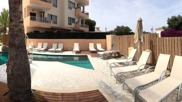 A pool area with lounge chairs and a wooden deck.