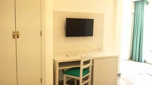 A room with a desk, a chair, a television mounted on the wall, and a wardrobe.