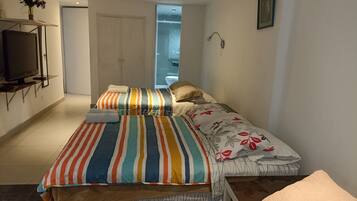 Quarto com cama, televisão e banheiro visível por uma porta aberta.