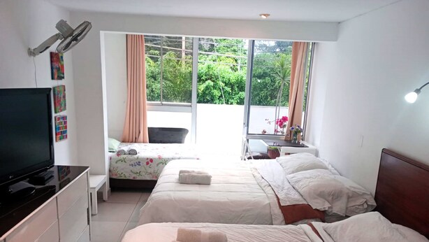 A hotel room with two beds, a TV, a desk, and a window with curtains.
