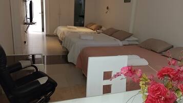 Habitación de hotel con dos camas, un escritorio, una silla y un baño visible a través de una puerta abierta.