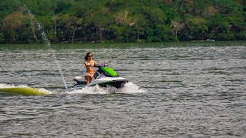 Una persona practicando esquí acuático en un lago con una orilla boscosa al fondo.