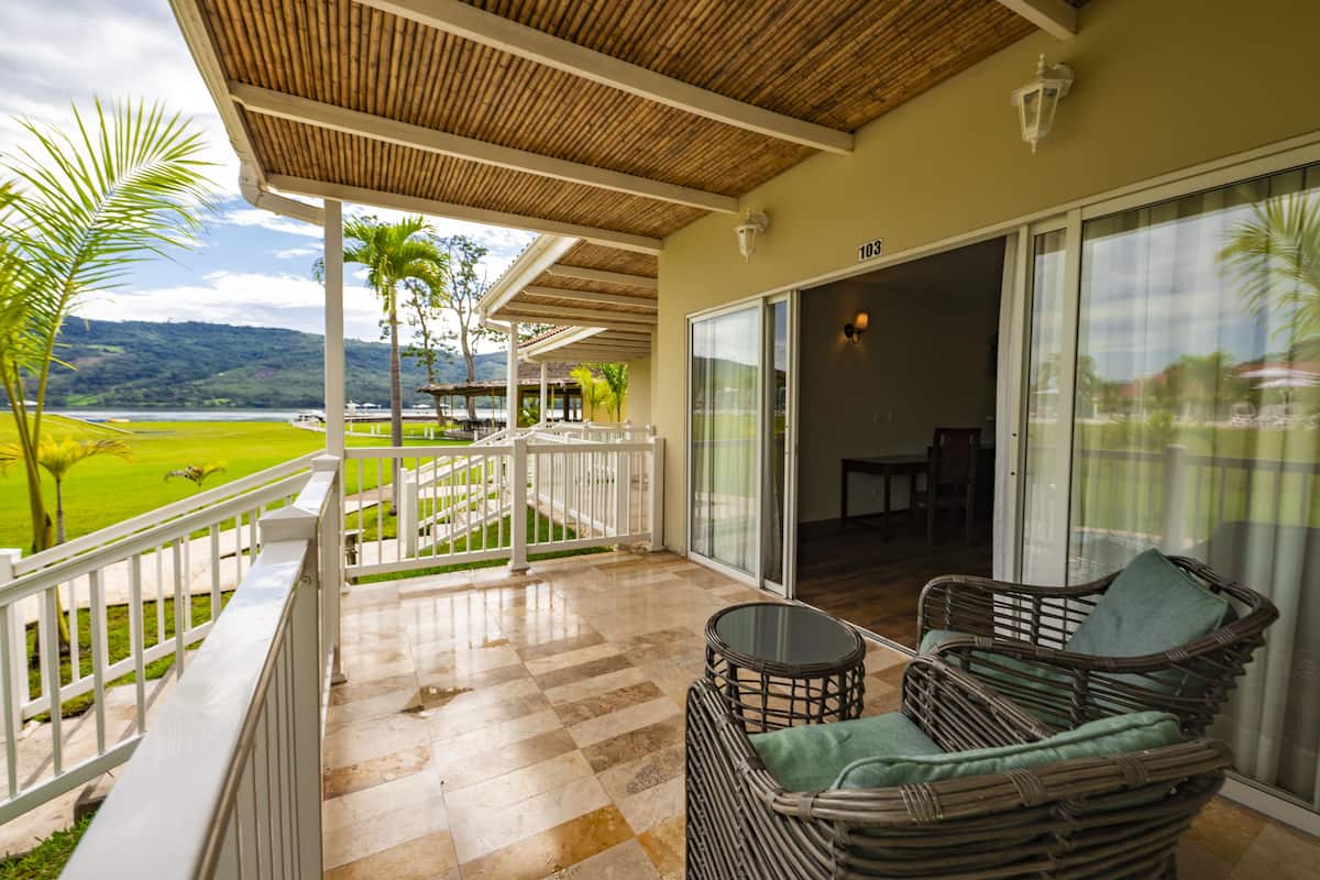 A balcony with a checkered floor, wicker furniture, and a view of a green landscape.