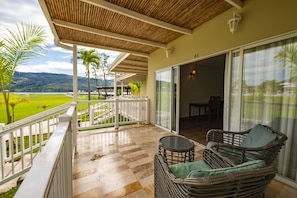 A balcony with a checkered floor, wicker furniture, and a view of a green landscape.