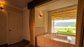 A bathroom with a large tiled bathtub, a door, and a window with a view of greenery. - Bella Terra Laguna Azul Resort & Spa (Sauce)